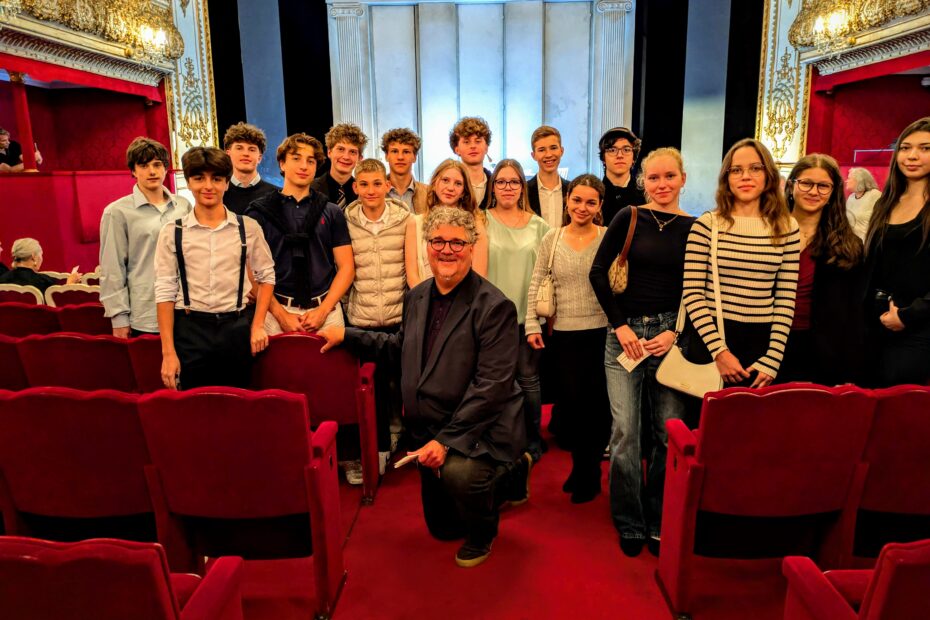 Junge Leute (eine Schulklasse) stehen vor einer Bühne in einem Theater